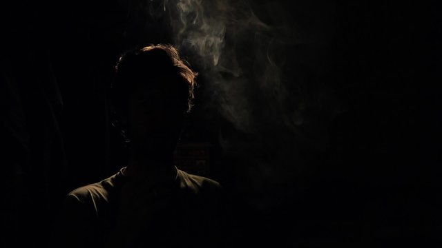 Back lit silhouette man smoking compulsively. Back Lit Silhouette of man smoking in a dark room - 1080p