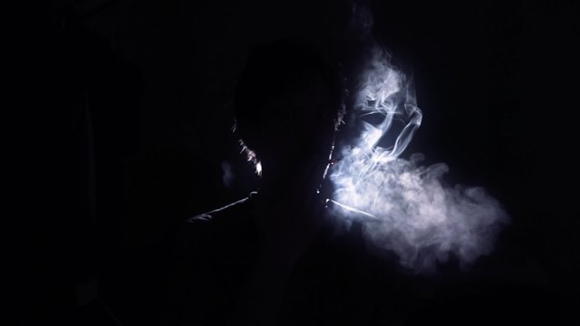 Cigarette smoker silhouette back lit man. Back Lit Silhouette of man smoking in a dark room - 1080p