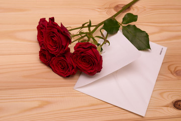 letter and red roses on wooden background