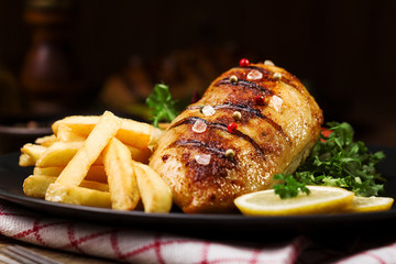 grilled chicken breast with green salad and french fries.