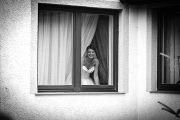 cheerful charming young bride smiles in the window