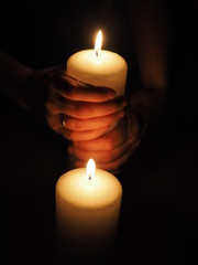candle and hands on a black background