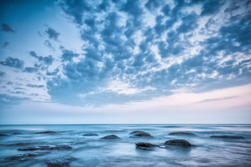 Landscape with blue skye, clouds and stones in the sea