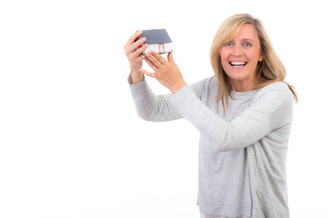 Fototapeta premium stolz präsentiert lachende frau ein miniaturhaus