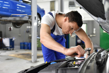 Automechaniker repariert Fahrzeug in einer Werkstatt // car mechanic repaired vehicle in a garage