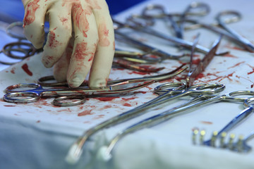 Surgeon's hand and bloody tools