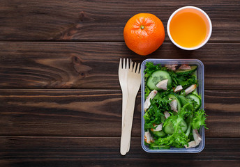 Lunch box with salad, apple, tangerine and juice.