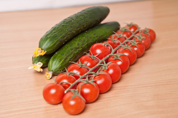 cherry tomatoes and cucumbers on a wooden background