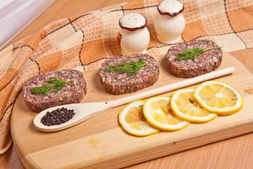 raw cutlets with lemon slices on a cutting board