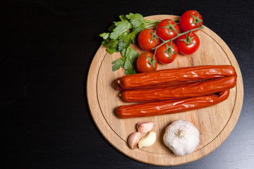 hunting sausages with vegetables and sauce on a cutting board on