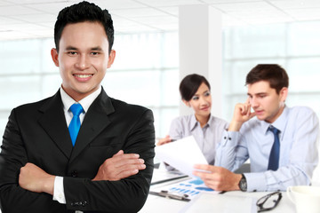 Young asian businessman, with his team behind. isolated in white