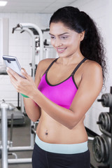 Fototapeta na wymiar Woman holds cellphone at gym