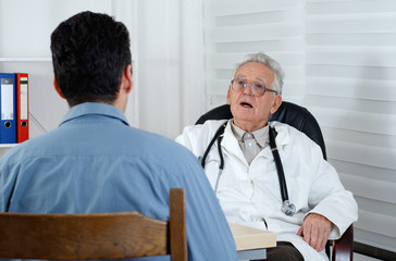 Fototapeta premium Male patient having consultation with old Doctor in consulting r