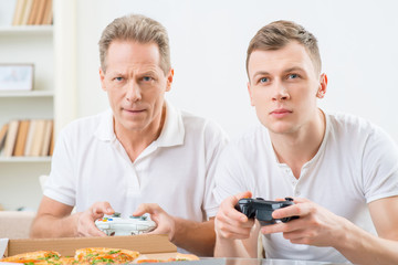 Father and adult son playing video games 