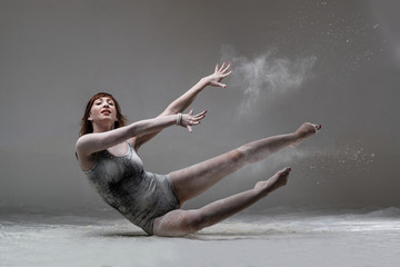 Beautiful expressive ballet dancer posing with flour at studio