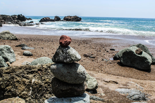 Steinturm am Strand mit rotem Stein obenauf