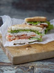 Chicken Club Sandwich with Lettuce and Tomato on old wooden