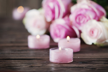 Fototapeta na wymiar Pink roses and pinl candles on the wooden table