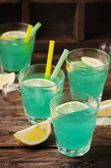 Green cocktail with lemon and ice on the wooden table