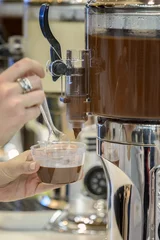 Crédence de cuisine en verre imprimé Chocolat main féminine avec une tasse de chocolat chaud et une machine à chocolat chaud