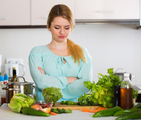 Young female with rotten vegetables at home
