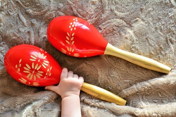 Couple of red wooden maracas and baby hand