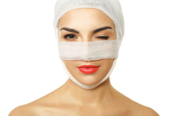 Young beautiful woman with a gauze bandage on her head and nose, isolated on white