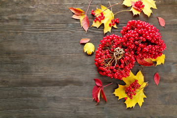 Autumn composition: bunch of viburnum and colourful leaves on wooden table