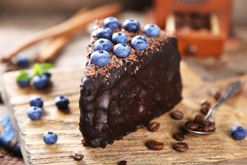 Chocolate cake with chocolate cream and fresh blueberries on plate, on wooden background