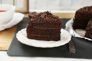 Sliced chocolate cake on wooden table, on light background