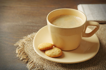 Cup of coffee, cookie and newspaper on wooden table background