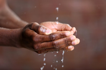 Hands washing concept. Water pouring into man hands on brick wall background