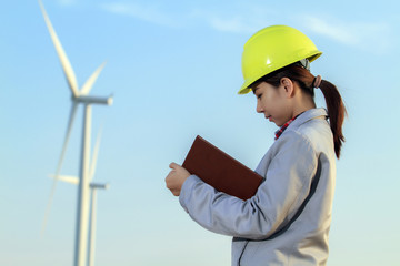 portrait women asia engineer working and holding blueprints at wind turbine farm Power Generator Station