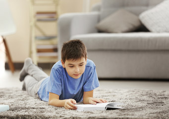 Boy reading book on a floor at home