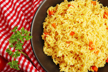 Stewed rice with a carrot on a black plate, close up