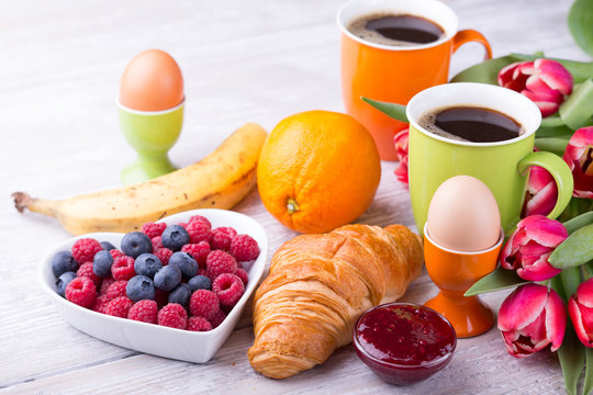 Sweet healthy breakfast with coffee, eggs, croissant and berries 