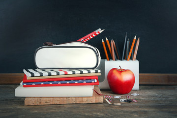 School supplies on old wooden table, near blackboard, close up