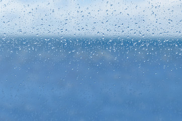 blur blue water and sky through transparent rainy window