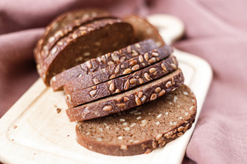 Sliced dark bread with crumbs on wood board
