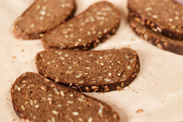 slices of black bread with sunflower seeds on paper