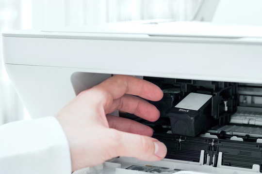 Man takes out black cardridge from white printer
