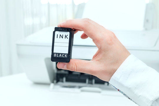 Man shows black ink cartridge from white printer