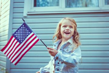Pretty little girl with long curly blond hair smiling and waving american flag. Independence Day, Flag Day concept. Vintage and retro toning