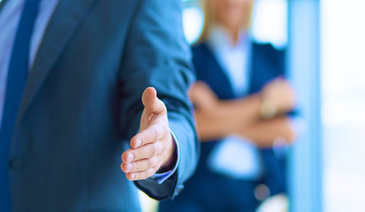 Young businessman ready to handshake standing in office