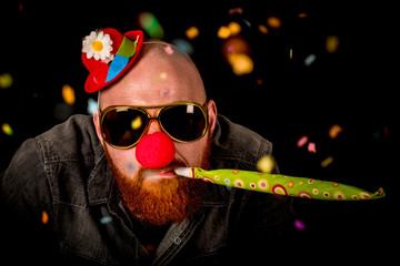 Man with beard wearing red nose, sunglasses and funny hat