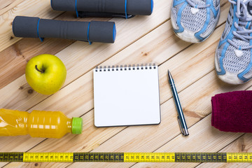 Sport Equipment. Dumbbells,  Shoes, Towel, Apple, Tape Measure, Orange  Juice And Notebook To Workout Plan On Wooden Table. Sport Fitness Background