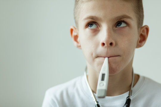 Thoughtful Boy With Digital Thermometer In Mouth