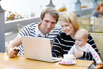 Young parents with their sweet baby in outdoors cafe