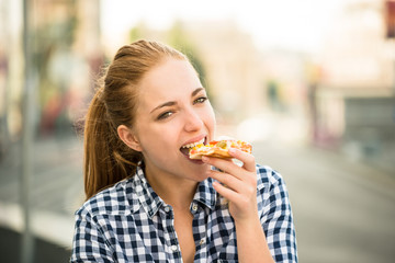 Teenager eating pizza in street