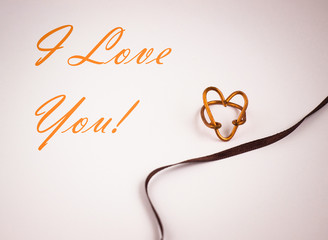 Heart shaped ring near ribbon closeup, i love you text